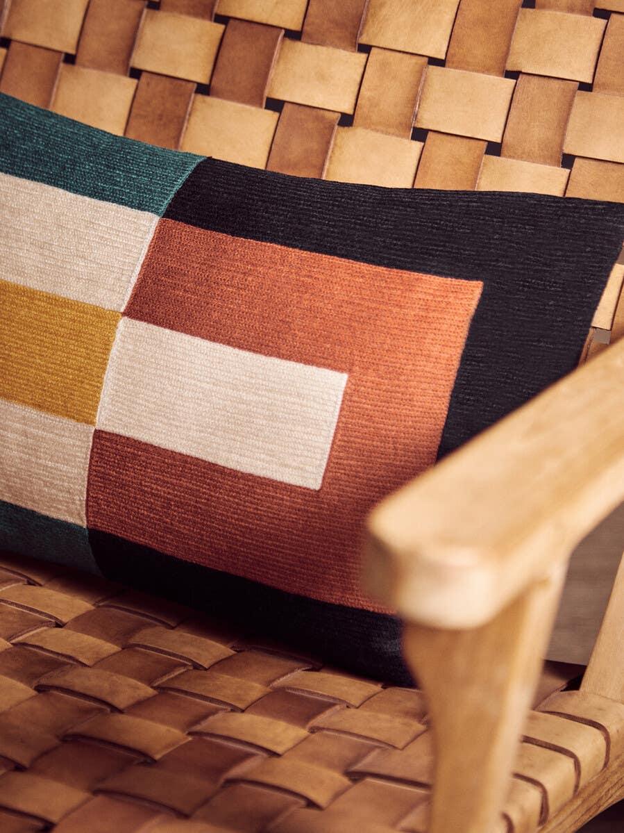 Woven leather armchair with geometric cushion in orange, green, cream and black