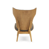 Dark grey velvet chair featuring a winged back design, supported by a light wood frame.