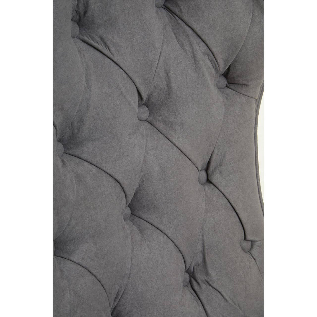 Close-up view of the dark grey velvet upholstery featuring a tufted design with button detailing, showcasing the soft texture and elegant curves of the winged back of the chair.