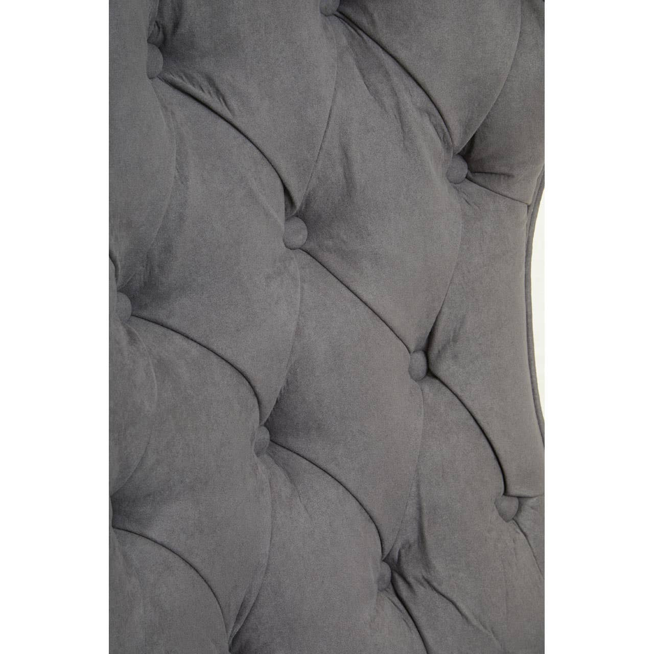 Close-up view of the dark grey velvet upholstery featuring a tufted design with button detailing, showcasing the soft texture and elegant curves of the winged back of the chair.