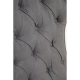 Close-up view of the dark grey velvet upholstery featuring a tufted design with button detailing, showcasing the soft texture and elegant curves of the winged back of the chair.
