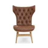 Brown leather effect chair featuring a winged back design with tufted detailing. The chair has a smooth, rounded seat and is supported by light-colored wooden legs.