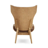 Brown leather effect chair featuring a winged back design, with a smooth, curved wooden frame and tapered legs.