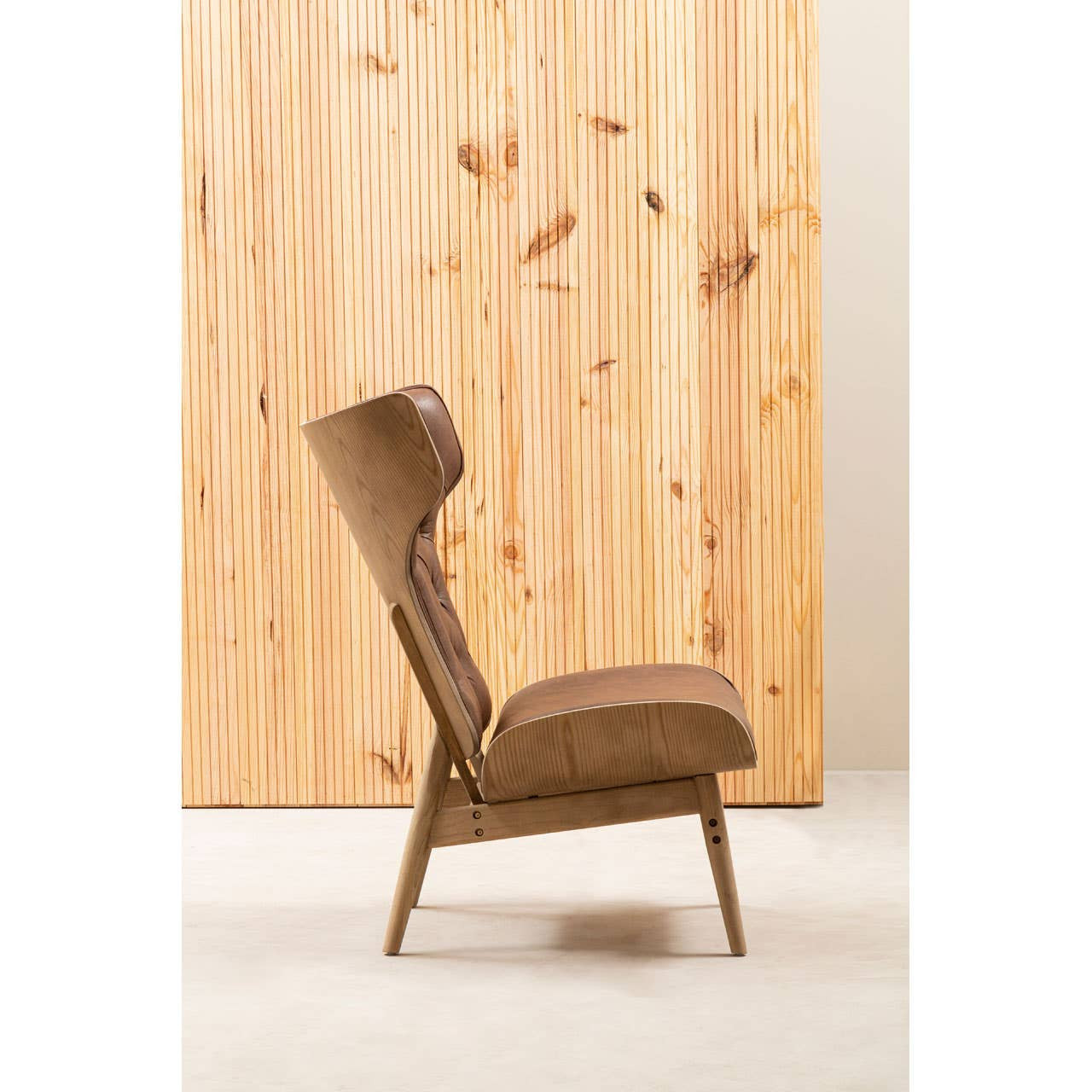 Brown leather effect chair featuring a winged back design, with a sleek, modern silhouette. The chair is supported by light-colored elm wood legs, showcasing a natural finish.