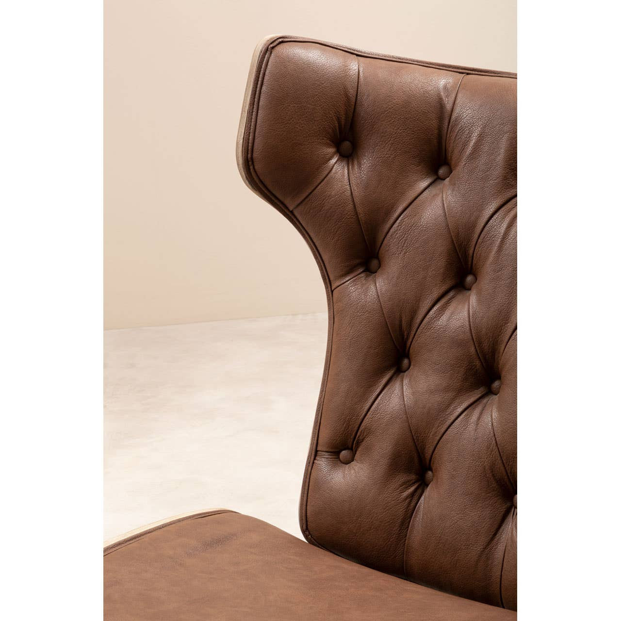 Brown leather effect chair featuring a winged back design with tufted detailing and button accents.