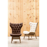 Brown leather effect chair featuring a winged back design and tufted upholstery, set against a textured wooden backdrop.