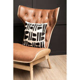 Brown leather effect chair featuring a winged back and tufted detailing, complemented by a decorative black and white patterned cushion.