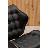 Black leather effect chair featuring a tufted design with rounded edges and buttons, set against a backdrop of natural wood paneling.
