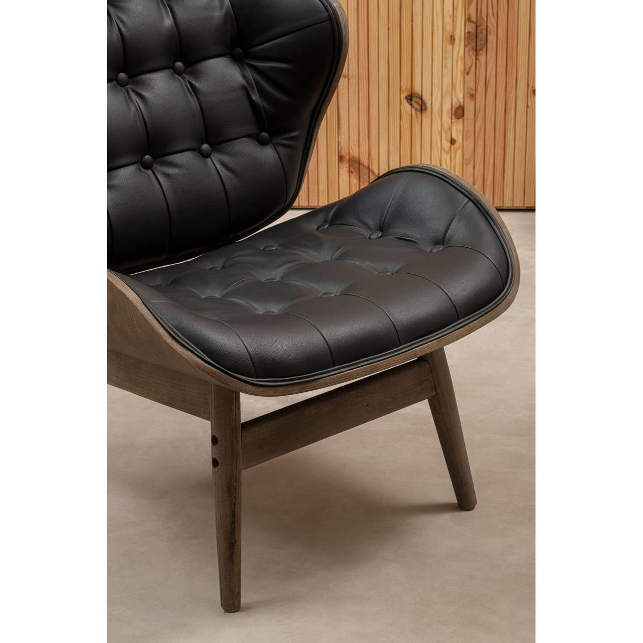 Black leather effect chair featuring a tufted design with button detailing, supported by a sturdy elm wood frame.
