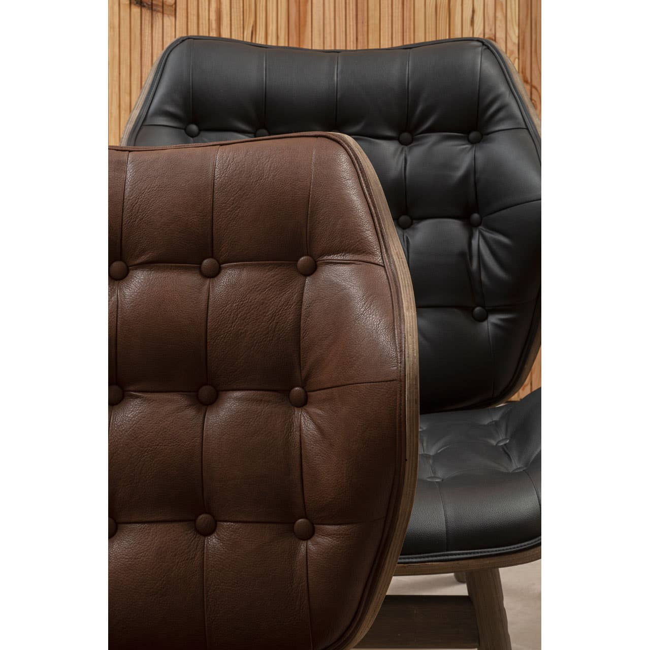 Black leather effect chair featuring button detailing, with a contrasting brown leather effect chair partially visible in the foreground.