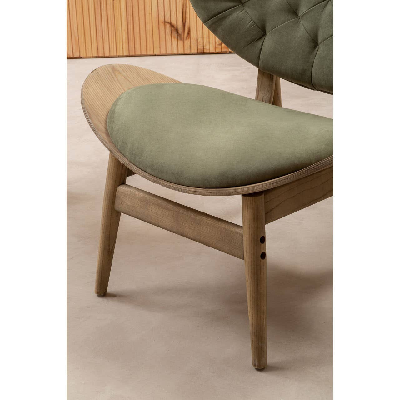 Green velvet chair featuring a plush, rounded seat and backrest, complemented by a light grey elm wood frame.