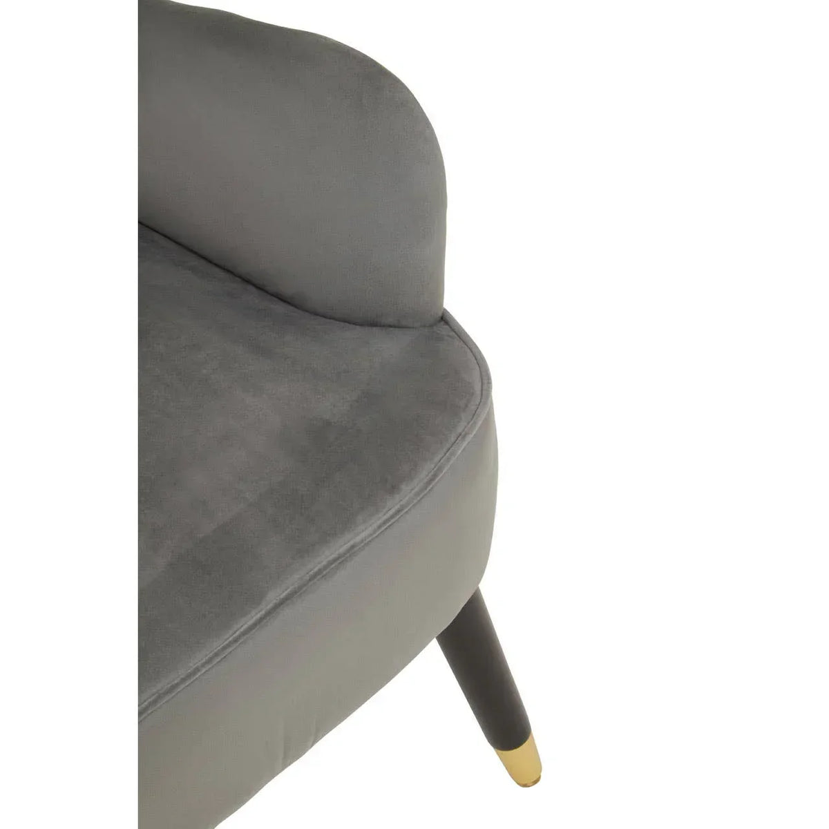 Close-up of grey velvet accent chair with rounded backrest and black legs with gold tips