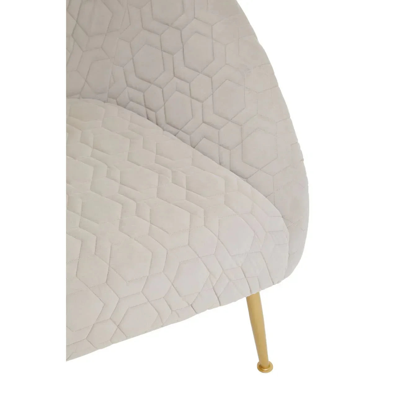Beige upholstered armchair with geometric stitching and gold metal leg, close-up view