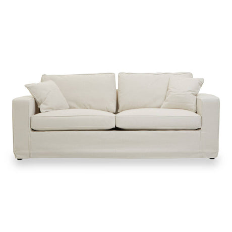 Cream fabric sofa with a modern design featuring two large seat cushions and two smaller accent pillows, resting on short, sturdy legs. The sofa has a clean, minimalist silhouette and is upholstered in a soft, textured fabric