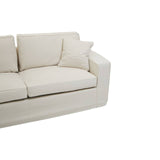 Cream fabric sofa with three seats, featuring plush back cushions and a single decorative pillow on one side. The sofa has a modern, minimalist design with clean lines and a sturdy base