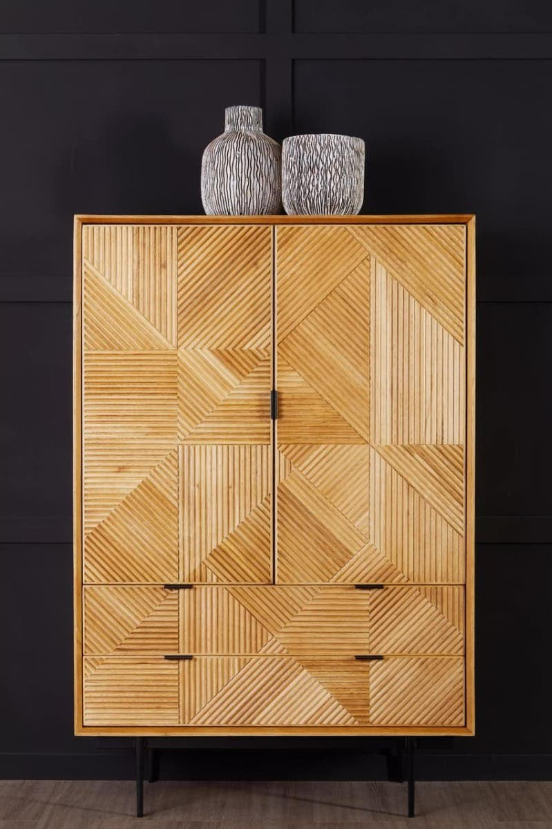 Natural wood cabinet featuring a geometric pattern on the front, with two doors and three drawers. The cabinet is finished in a light natural tone and stands on slender black legs. Two decorative vases are placed on top against a dark background