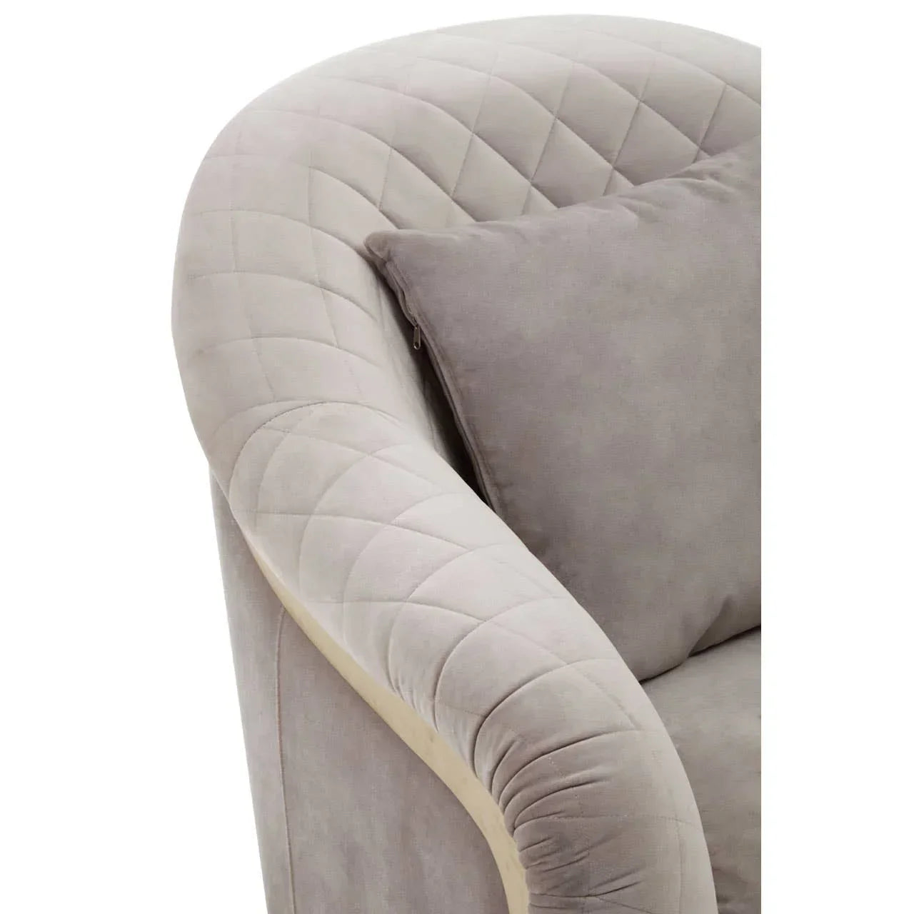 Close-up of light grey velvet sofa arm with quilted stitching and matching cushion