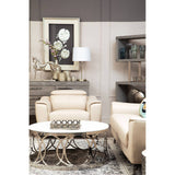 A stylish living room featuring the Padua 3 Seat Stone Leather Sofa with adjustable headrests, complemented by a beige armchair and a round coffee table with decorative items. The backdrop includes a framed artwork and a lamp, creating a cozy and modern atmosphere