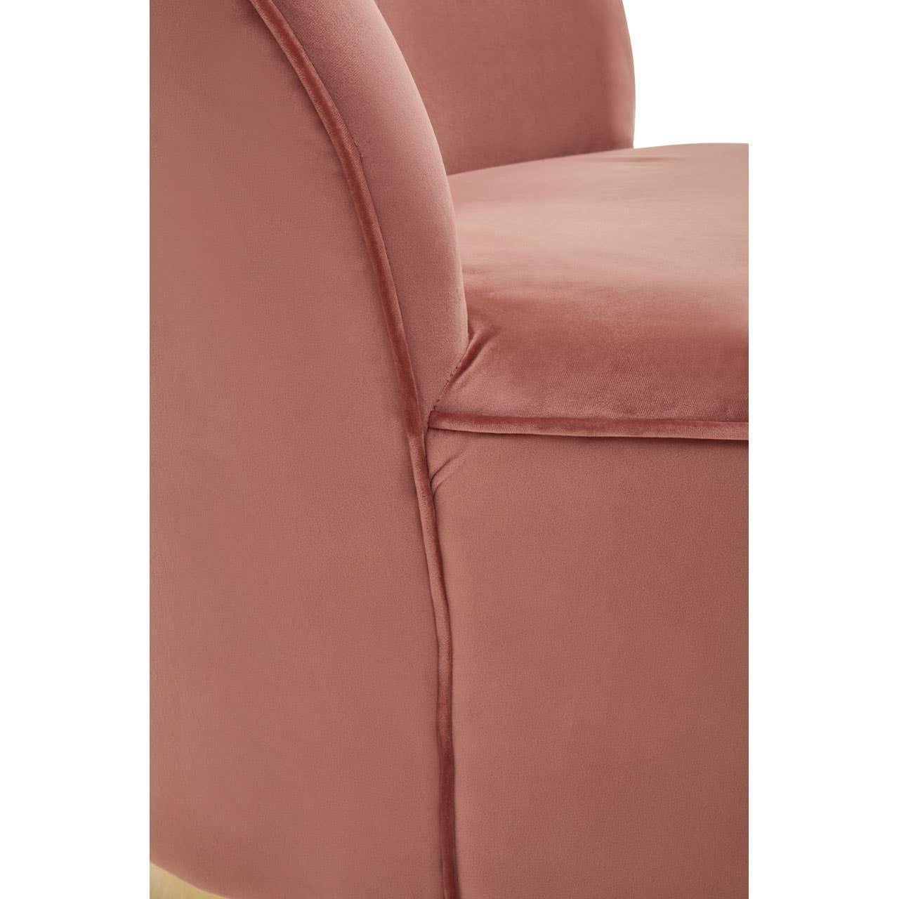 Close-up of pink velvet armchair upholstery and curved armrest