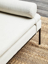Cream fabric sofa with bolster cushion and black metal legs on woven rug