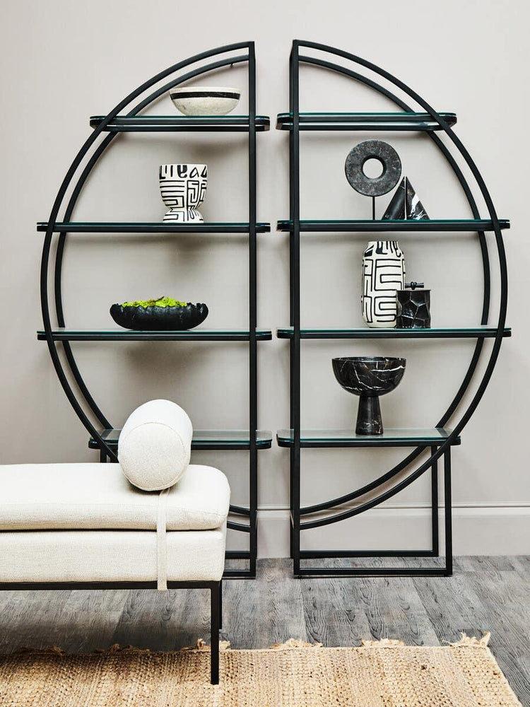 Black metal and glass shelving unit with geometric decor beside modern cream bench