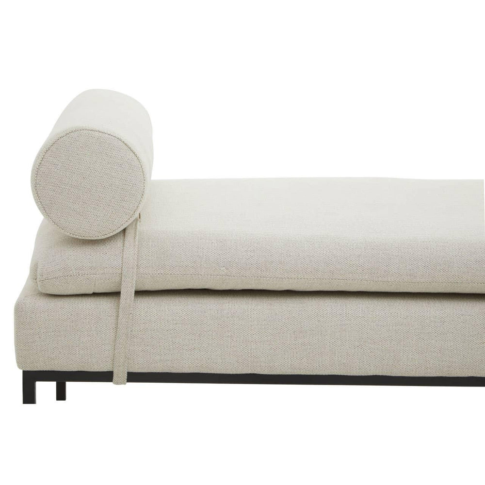 Beige upholstered daybed with round bolster cushion and black metal legs, side view