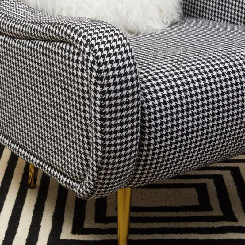 Houndstooth armchair with gold legs and white cushion on geometric black and white rug