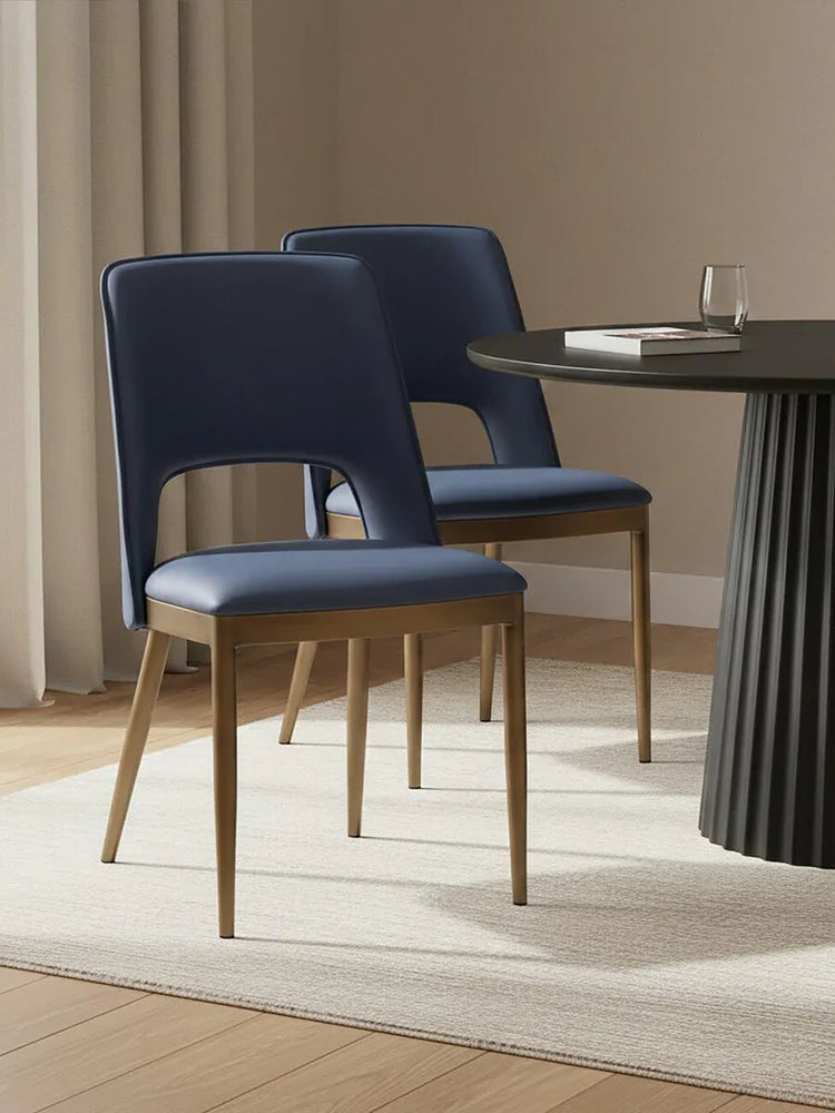 Navy blue dining chairs with wooden legs beside round black dining table on cream rug