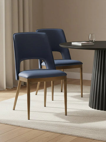 Navy blue dining chairs with wooden legs beside round black dining table on cream rug