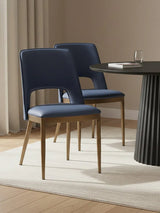 Navy blue dining chairs with wooden legs beside round black dining table on cream rug