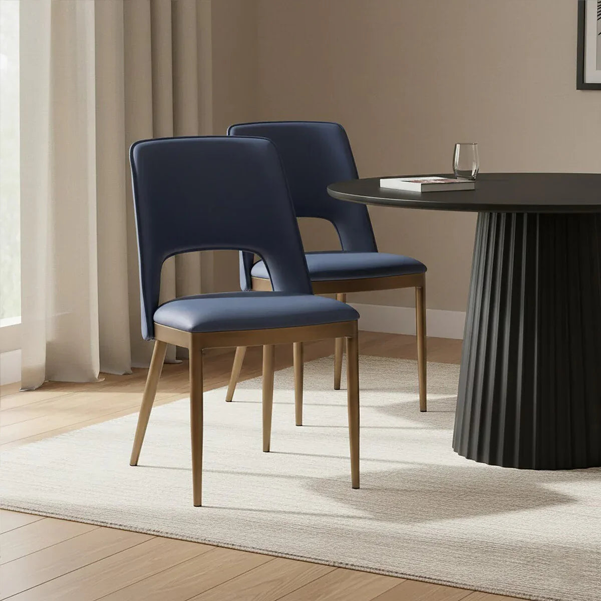Navy blue dining chairs with wooden legs beside round black dining table on beige rug