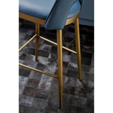 Blue upholstered bar stool with gold metal legs on dark tiled flooring