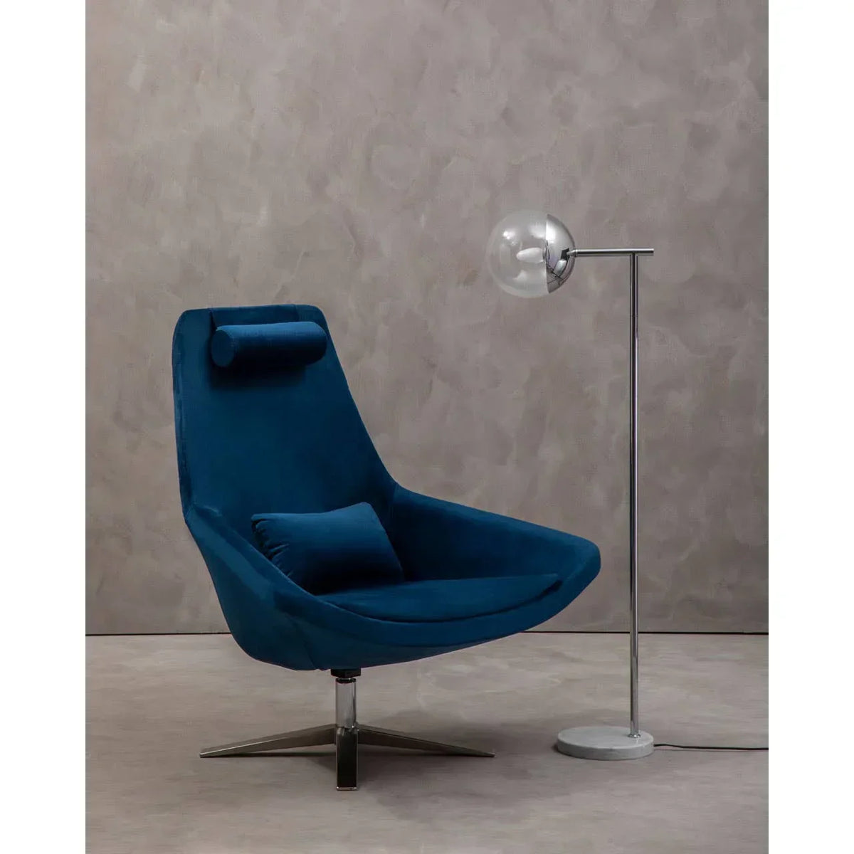 Blue velvet swivel armchair with chrome base beside modern floor lamp on neutral background