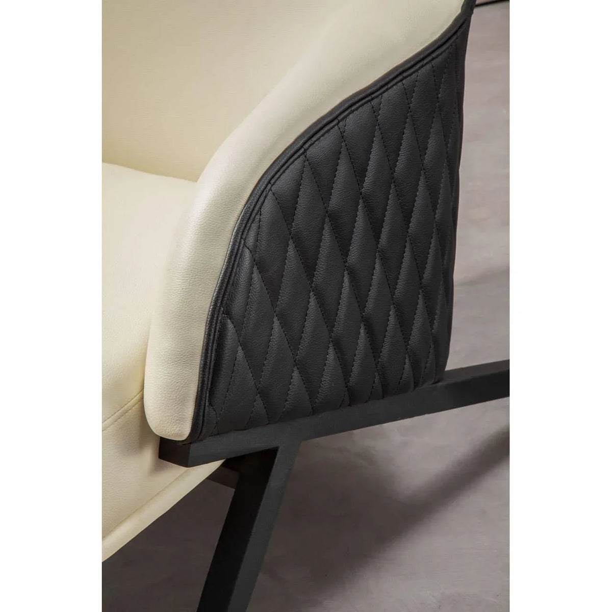 Black quilted faux leather armchair armrest with cream upholstery and black metal frame