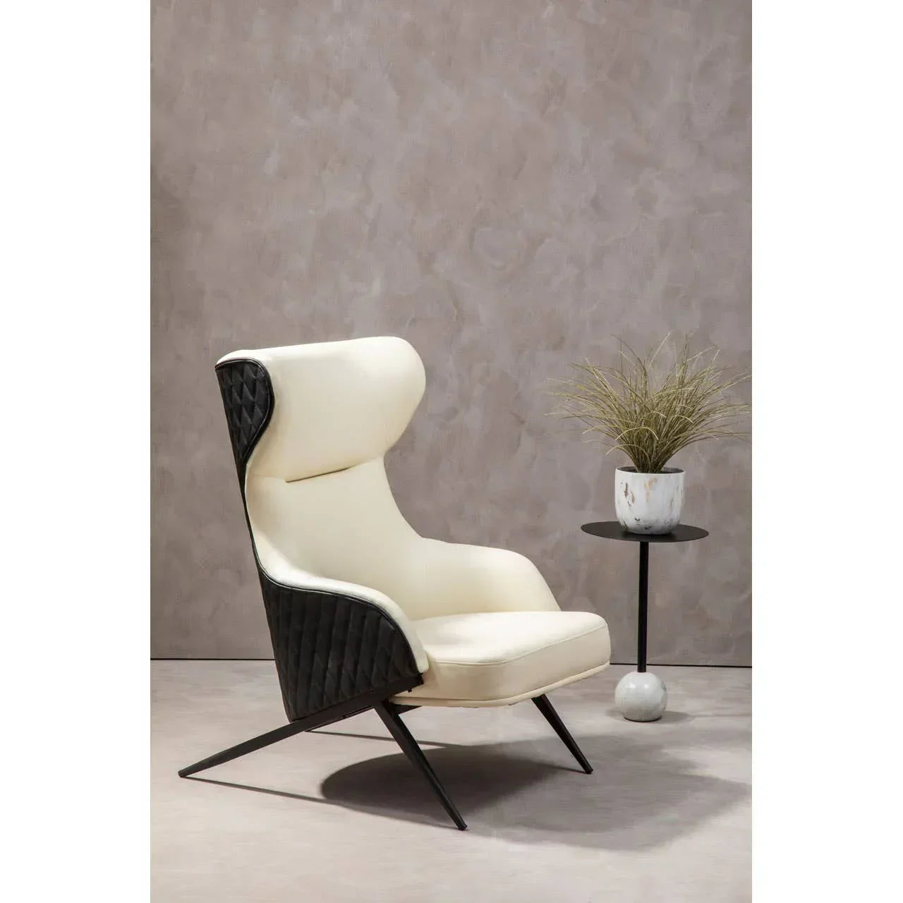 Modern accent chair with cream upholstery and black quilted sides beside round side table