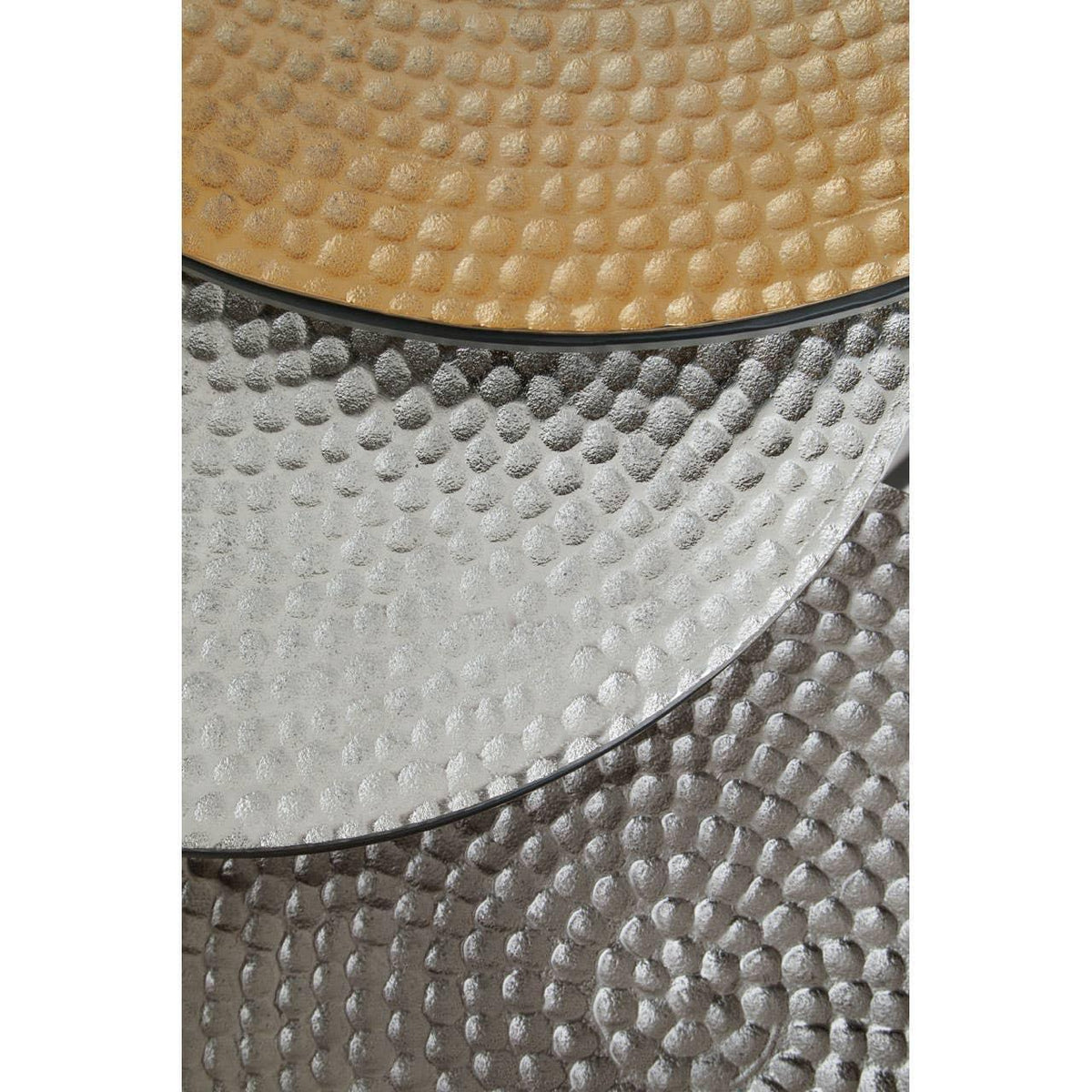 Close detail of nested metallic coffee table tops with hammered texture in gold and silver finish