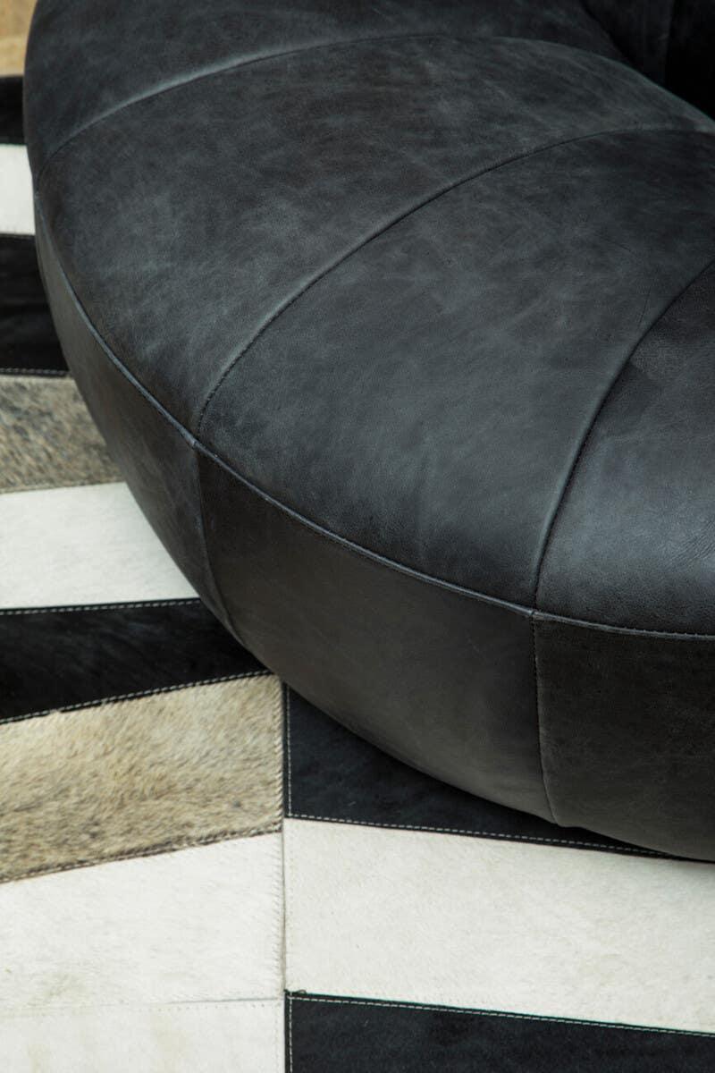 Close-up of black leather sofa corner on patterned cowhide rug