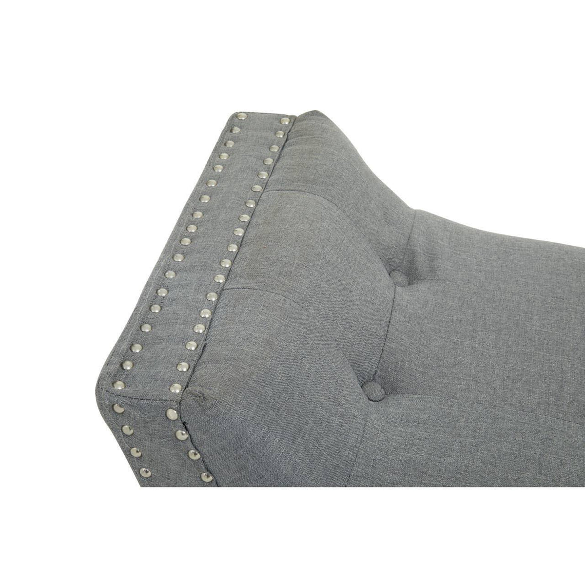 Grey upholstered sofa backrest with button tufting and metal stud detailing
