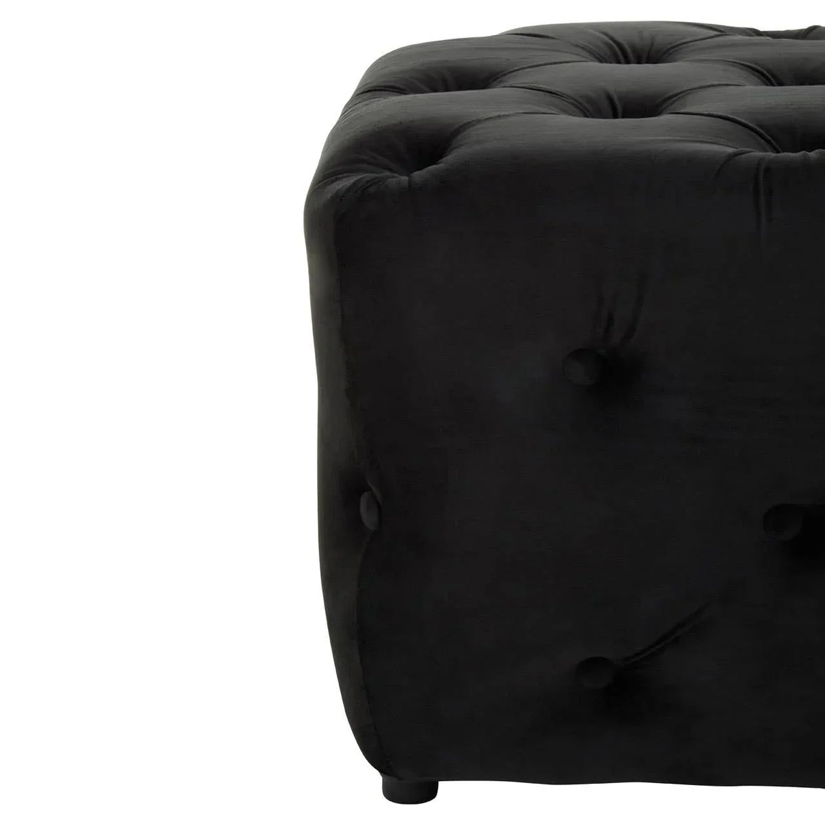 Closeup of black velvet ottoman with deep button tufting and rounded corner