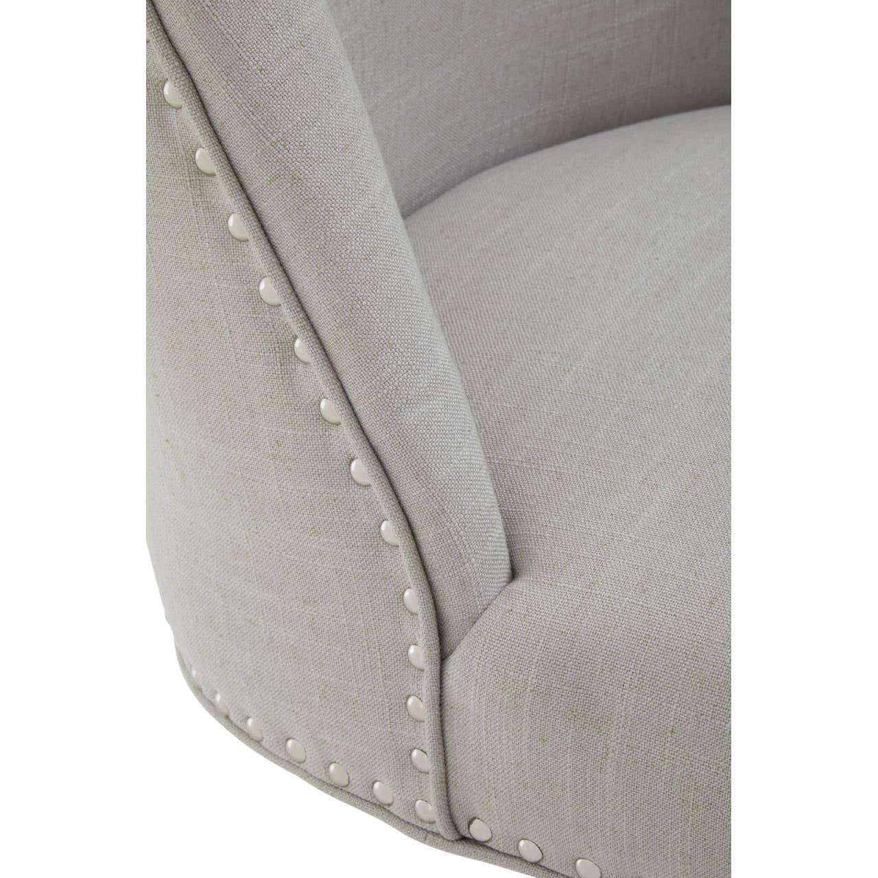 Close-up of beige fabric armchair with silver stud trim and soft seat cushion