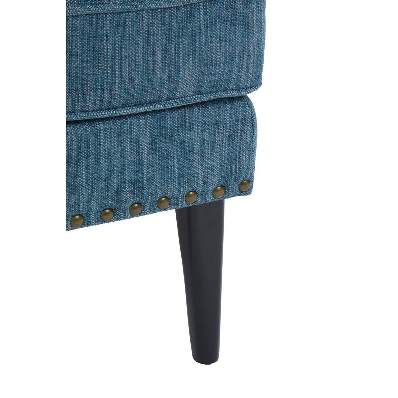 Blue fabric sofa corner with brass stud detailing and black wooden leg