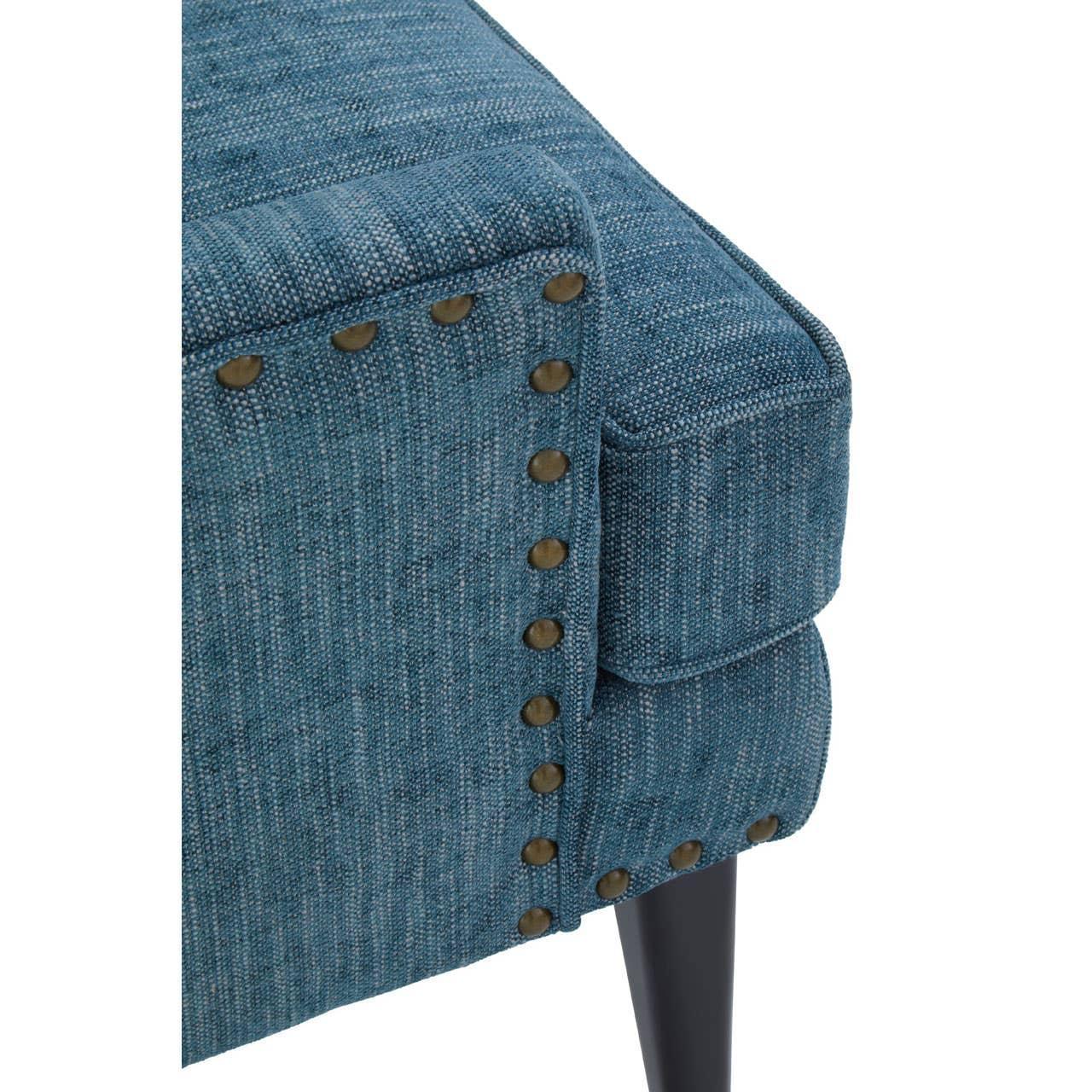 Blue fabric sofa corner with nailhead trim and dark wooden leg close-up