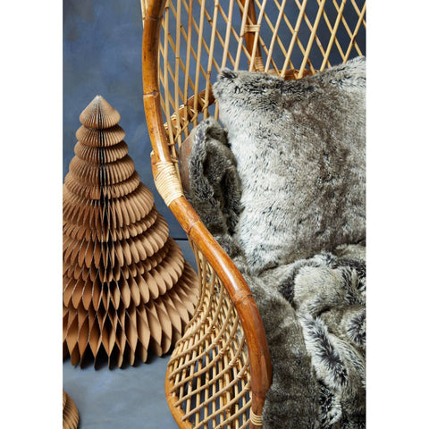 High back chair made of natural rattan with a woven design, featuring a curved frame and a plush, textured cushion. The background is a soft blue, enhancing the chair's warm tones