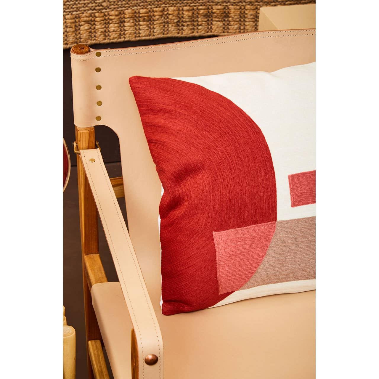 Modern decorative cushion with red and beige geometric pattern on a beige leather chair