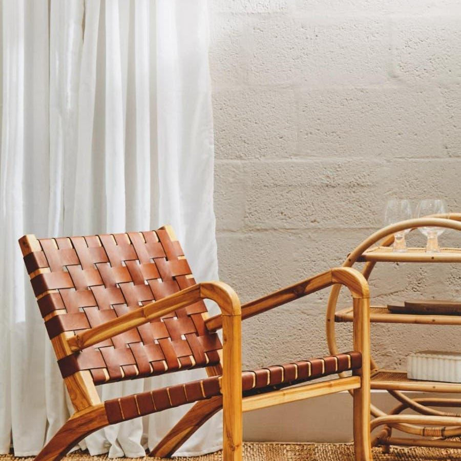 Leather lounge chair with wooden frame beside rattan drinks trolley on woven rug