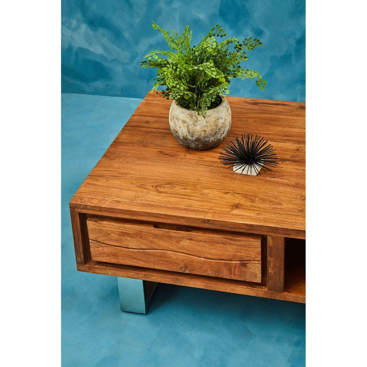 Rectangular wooden coffee table with metal legs, drawer, potted plant and decor accent