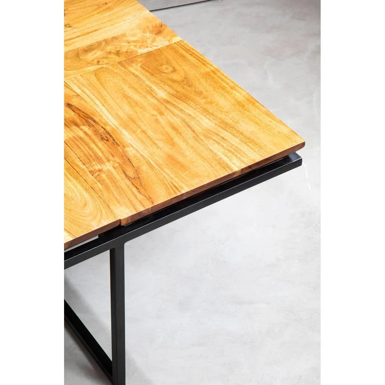 Closeup of dining table with light wood top and black metal frame on concrete floor