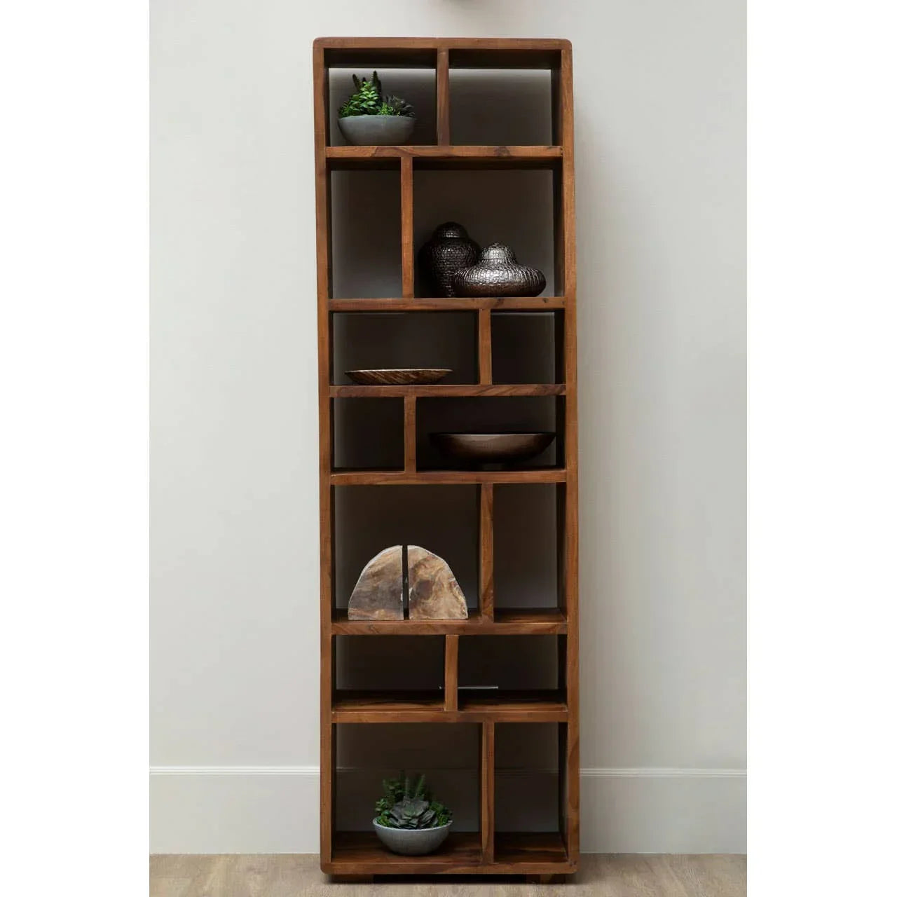Tall wooden display unit with open shelves, decorative bowls, ornaments, and potted succulents