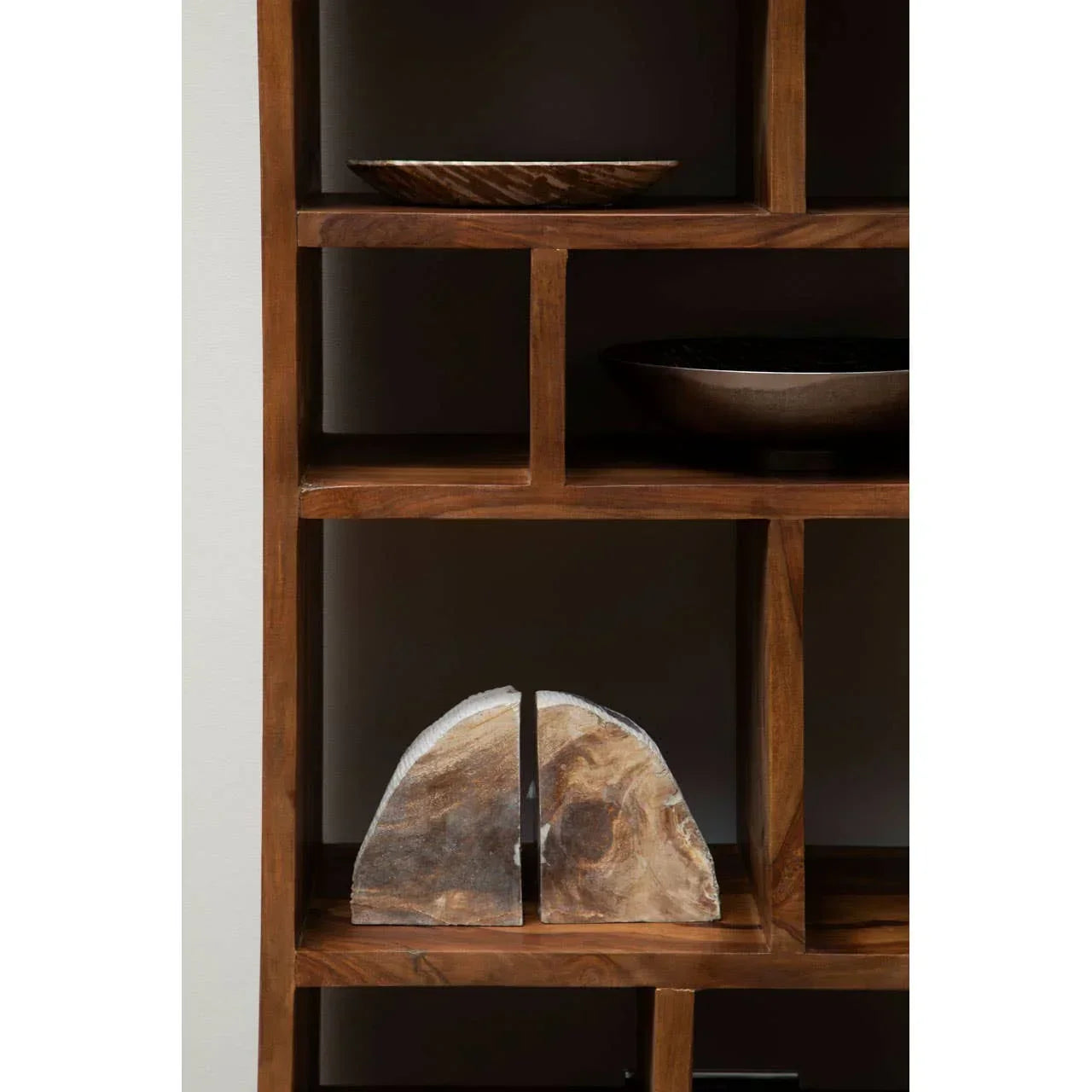 Wooden bookcase with decorative bowls and geometric stone bookends on shelves