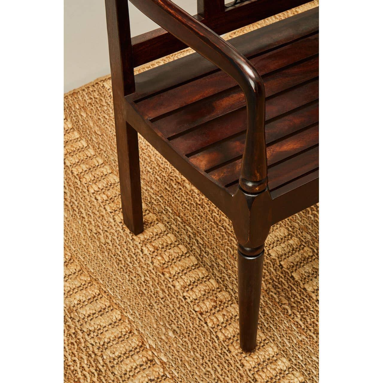 Close up of dark wood armchair leg and slatted seat on woven rug